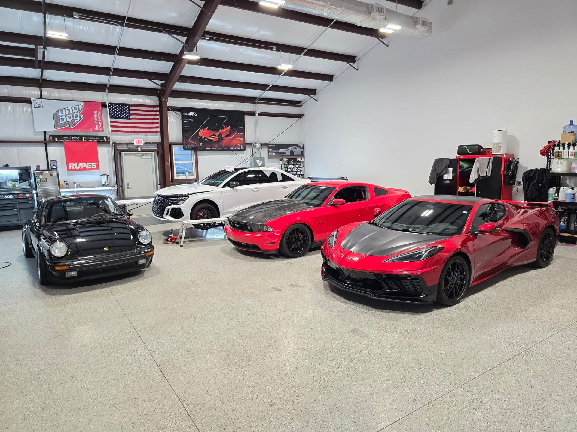 Lowcountry Detail Center shop bay with a Porsche, Audi, Mustang, and Corvette in for window tinting